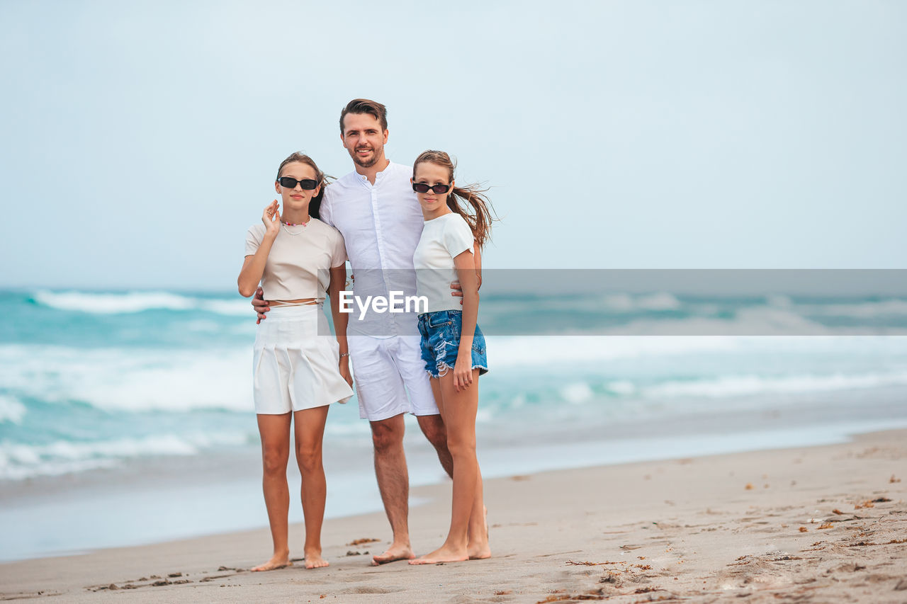 friends standing at beach against sky