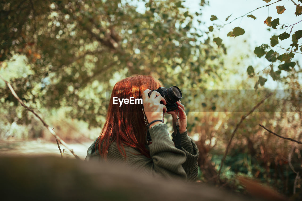 Woman holding camera while standing during winter