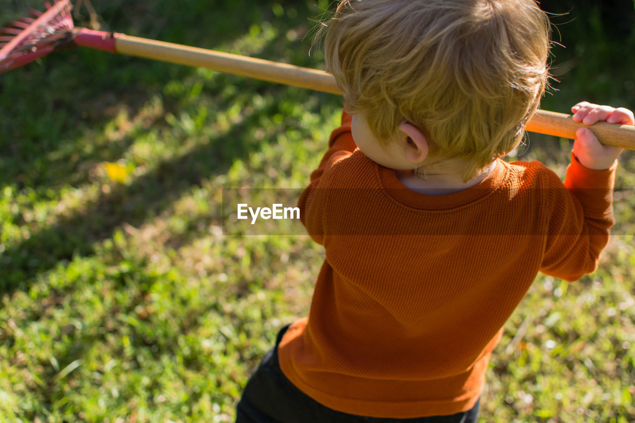 Boy holding rake in yard