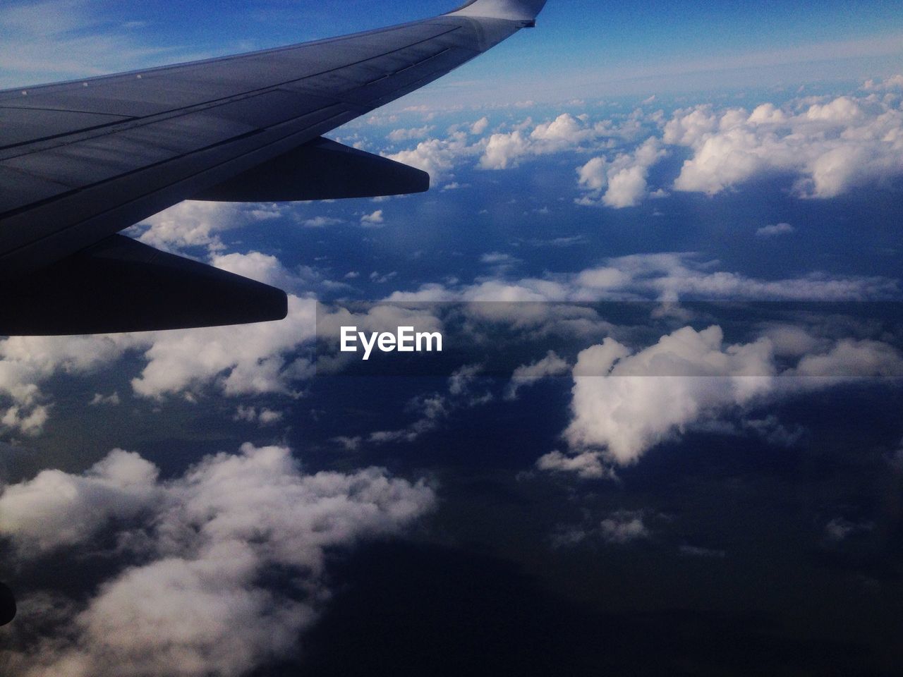 CROPPED IMAGE OF AIRPLANE FLYING OVER CLOUDY SKY