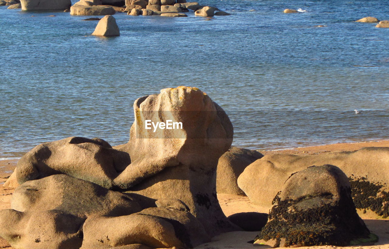 Rocks by lake on sunny day