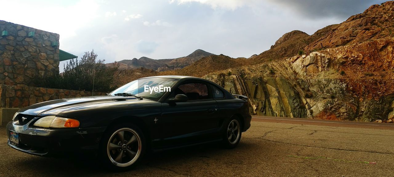 VINTAGE CAR ON ROAD AGAINST MOUNTAIN