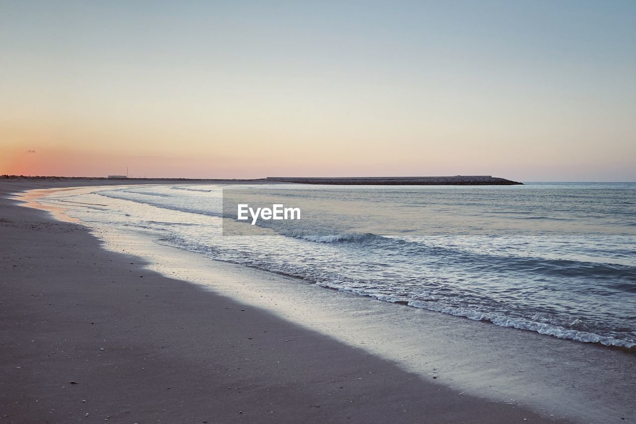 SCENIC VIEW OF BEACH AGAINST SKY DURING SUNSET