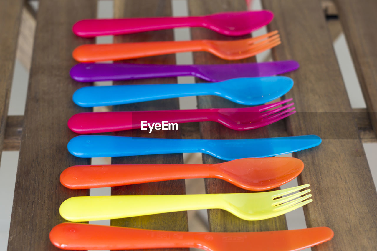 Close-up of colorful plastic eating utensils on wooden table