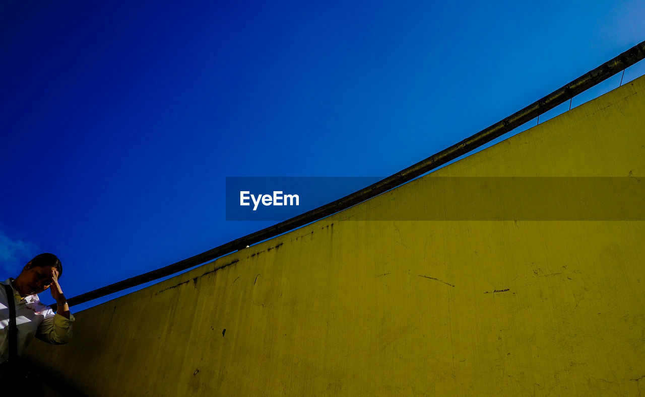 LOW ANGLE VIEW OF PERSON AGAINST CLEAR BLUE SKY