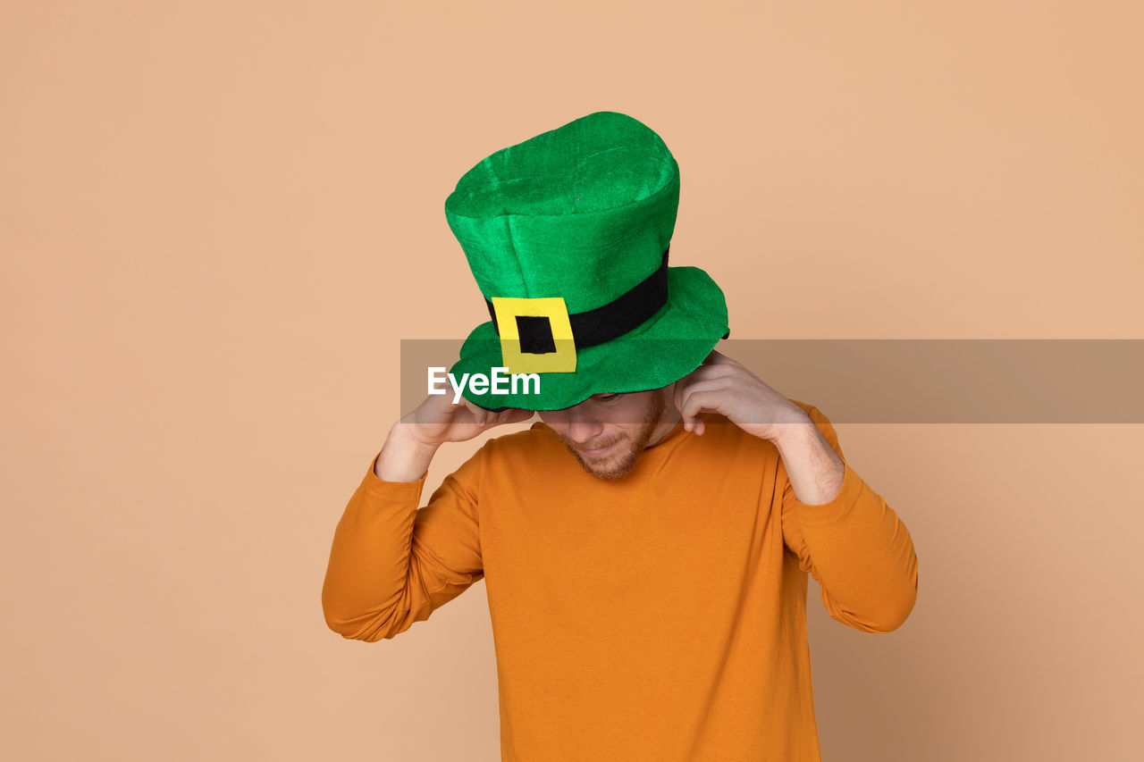 Man wearing green hat standing against beige background