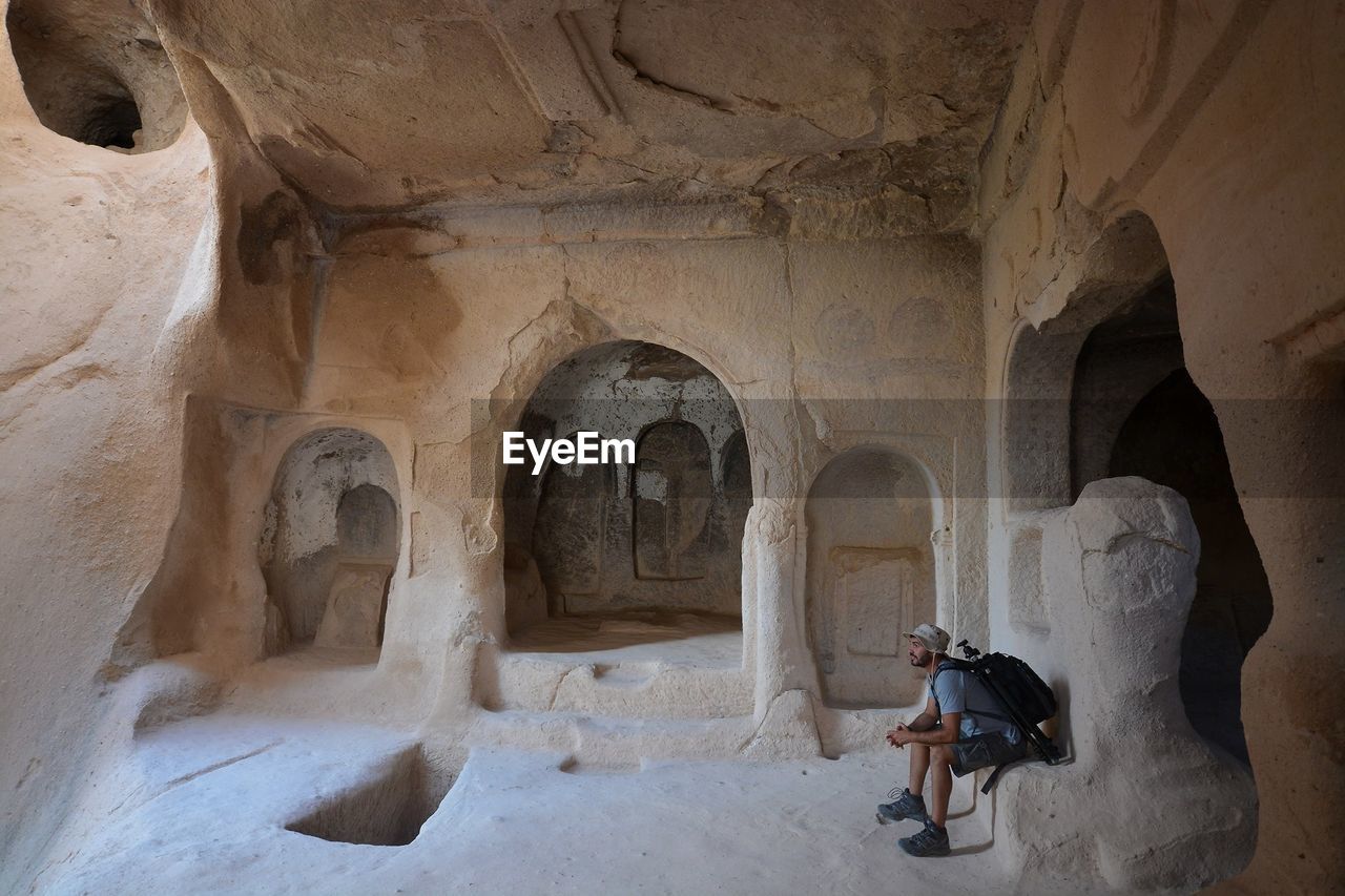 Side view of tourist sitting in cliff dwelling at zelve monastery