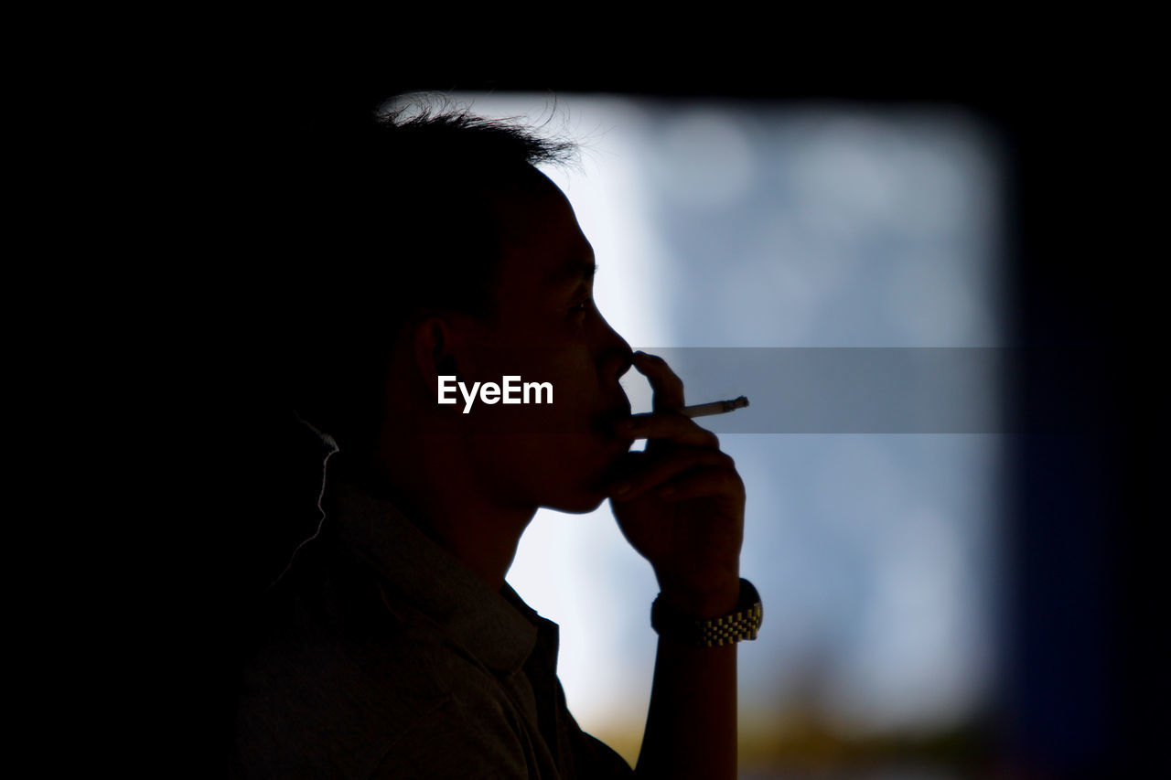 Close-up of man smoking cigarette at night