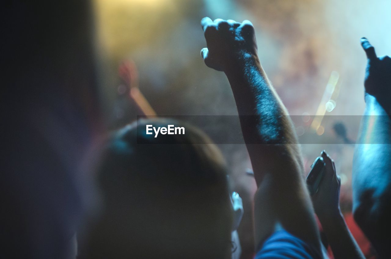 People with arms raised enjoying at music concert