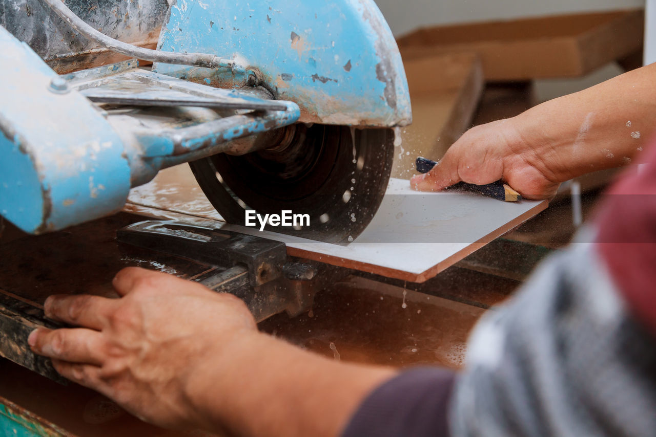 Cropped image of manual worker using machinery while working at factory