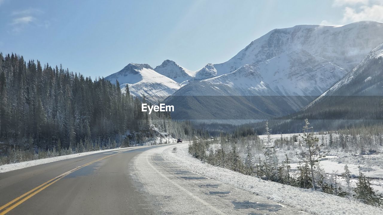 Road amidst snowcapped mountains against sky