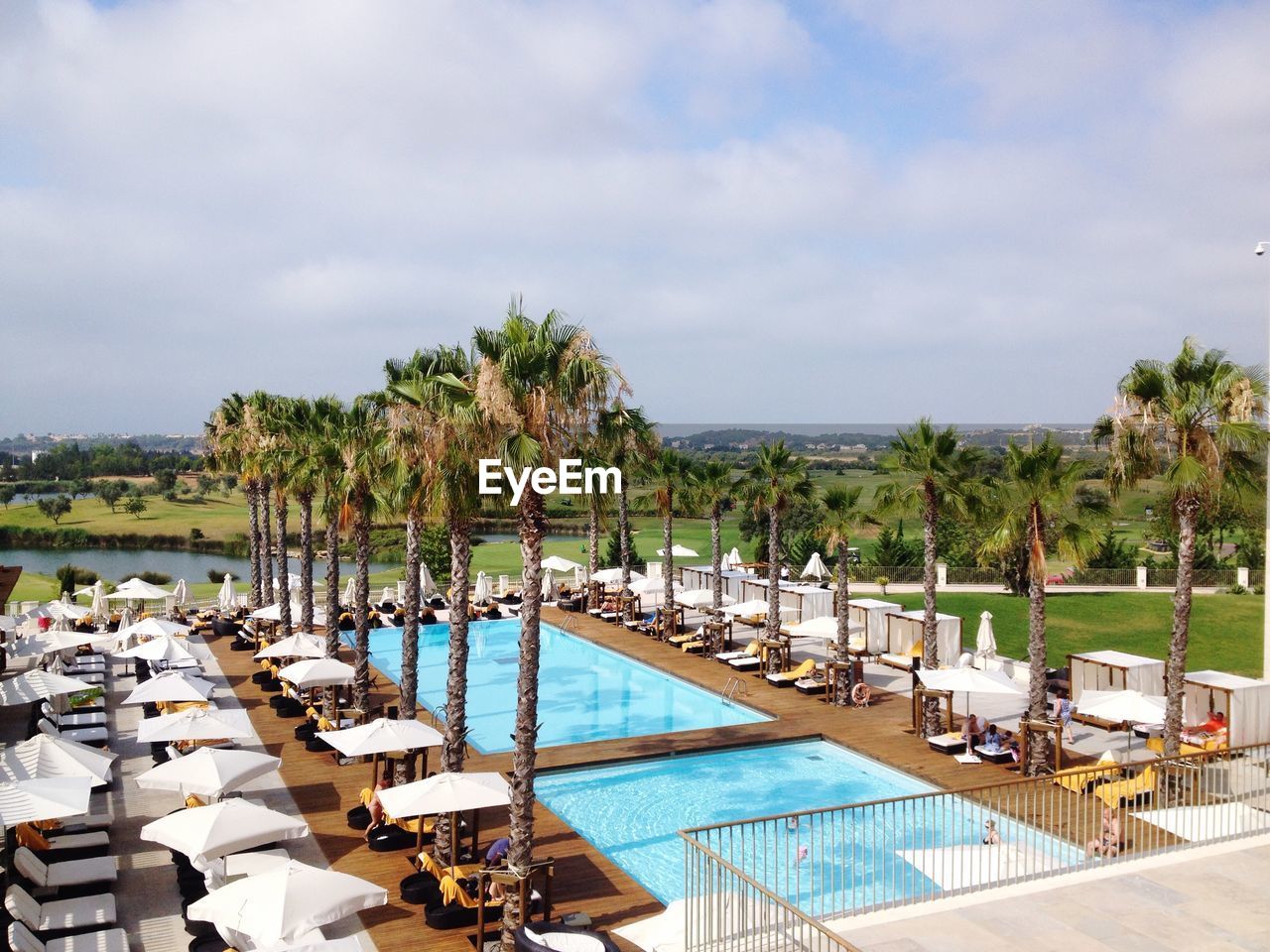 People by poolside in luxury hotel against sky