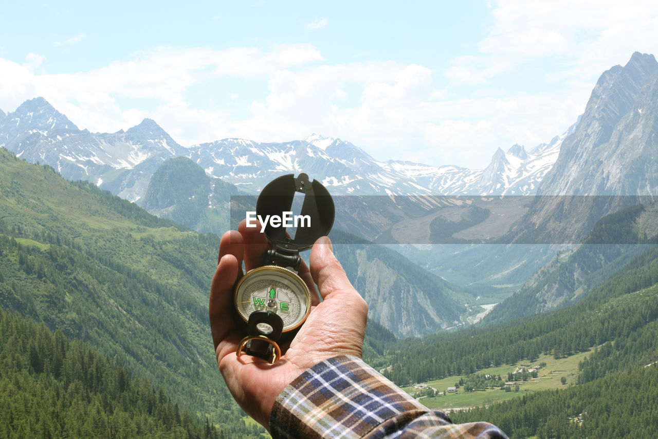 MAN HOLDING HANDS AGAINST MOUNTAINS