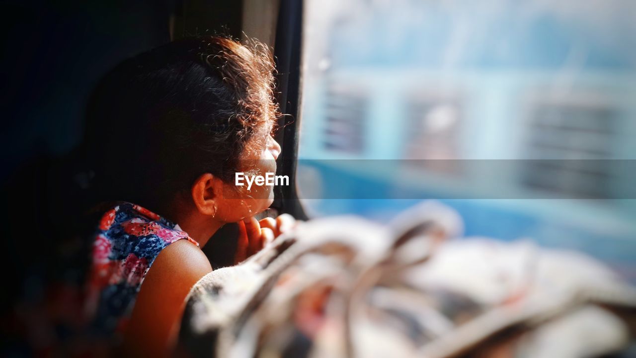 Side view of woman looking through train window