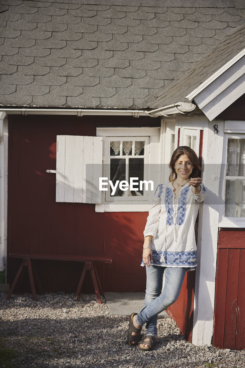 Smiling woman standing in front of wooden house