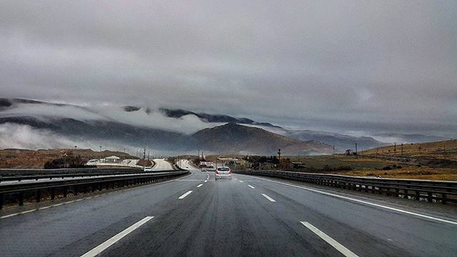 ROAD LEADING TOWARDS MOUNTAINS AGAINST CLOUDY SKY