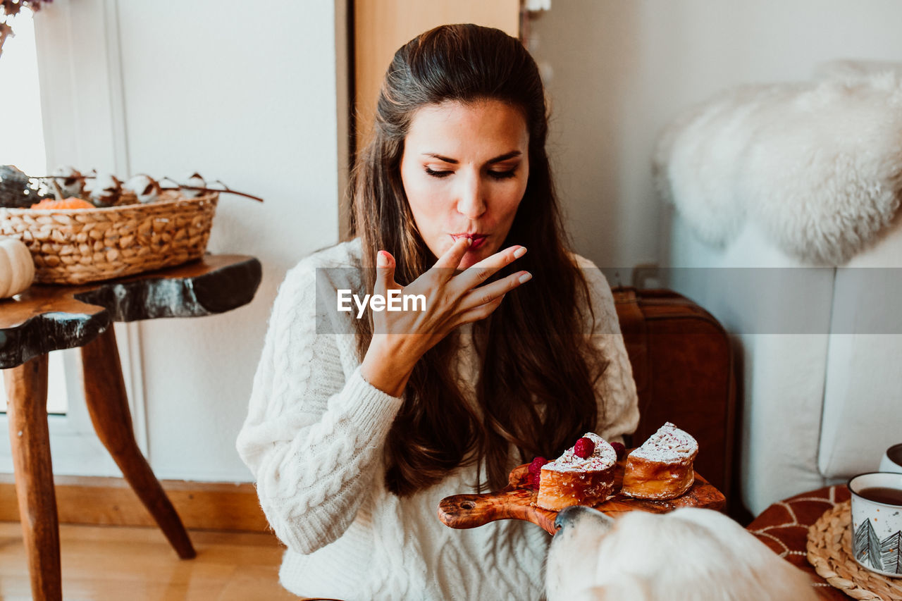 Woman eating sweet food while sitting at home