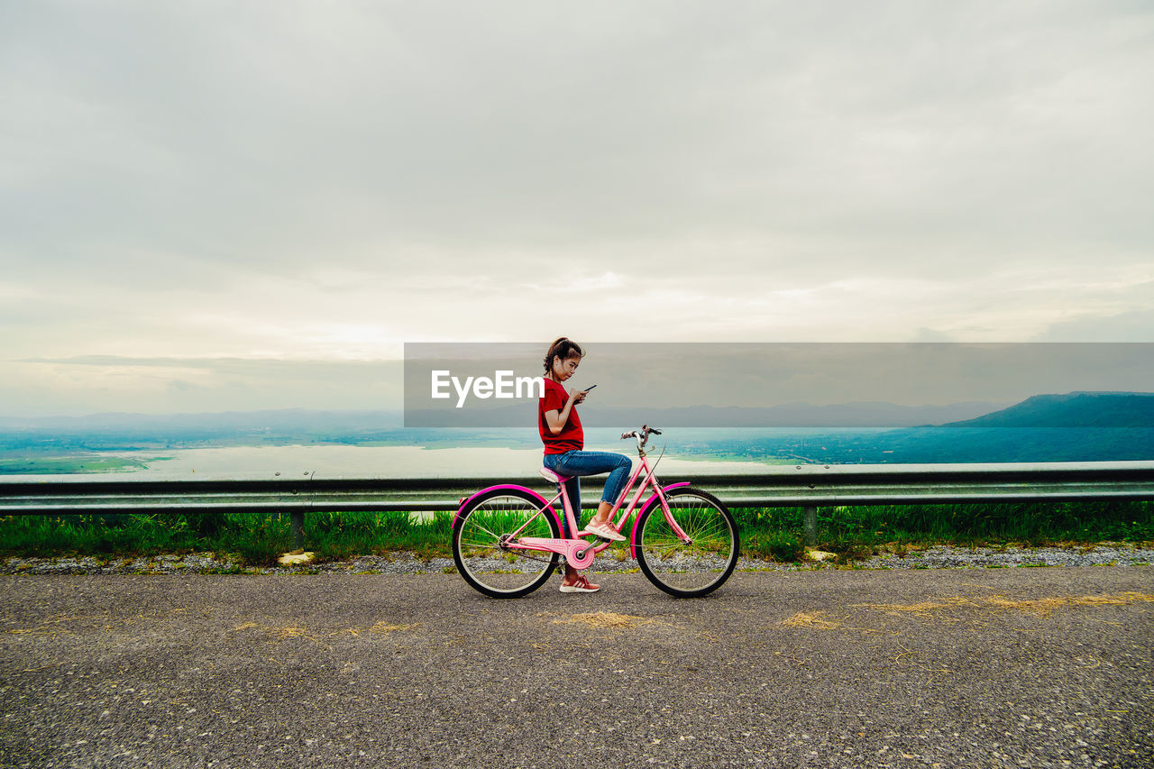 Man riding bicycle on road against sky