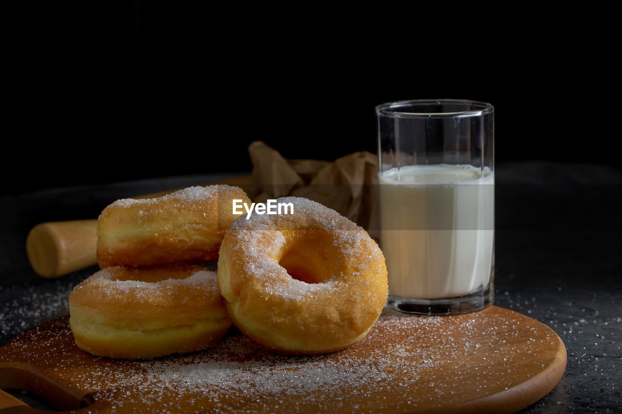 Donuts with sugar on a wooden plate on a dark table background