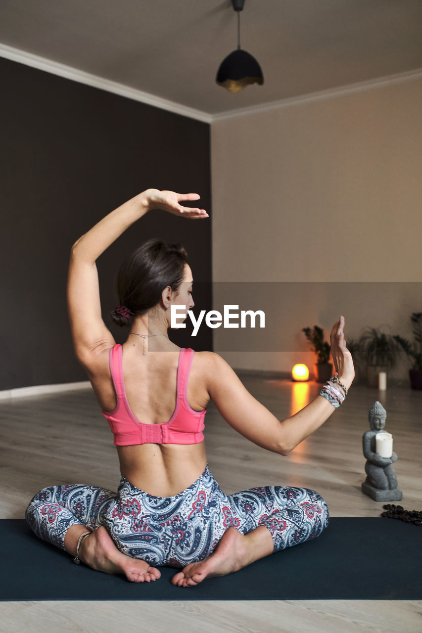 Young woman doing yoga on yoga mat in atmospheric yoga studio