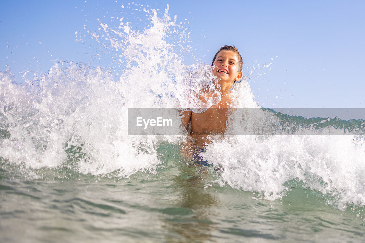 Funny kid playing with waves on the beach