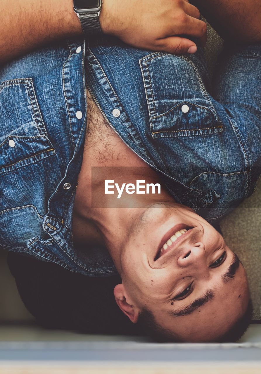 Portrait of smiling young man lying at home