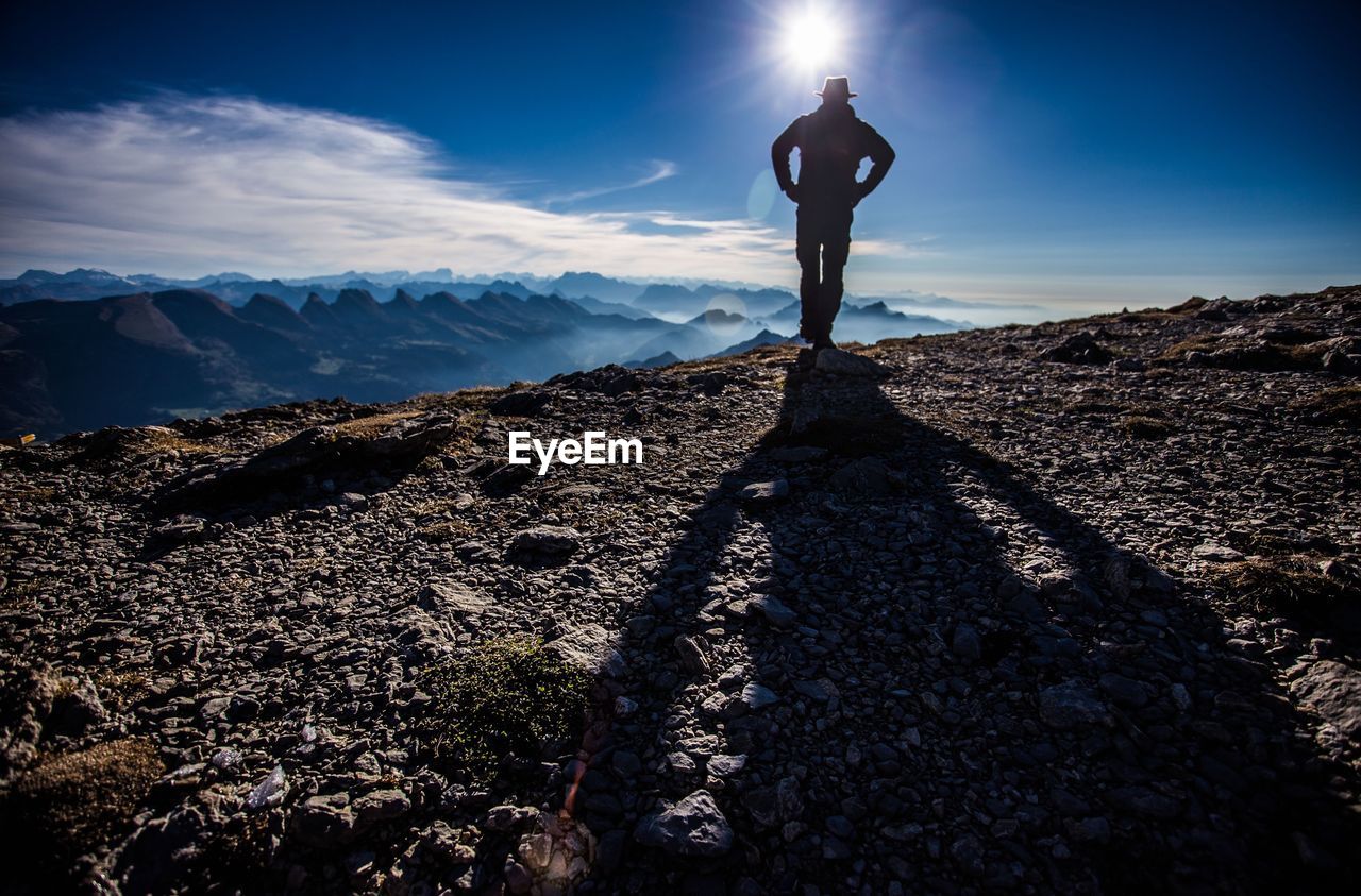 Rear view of man standing on mountain against sky