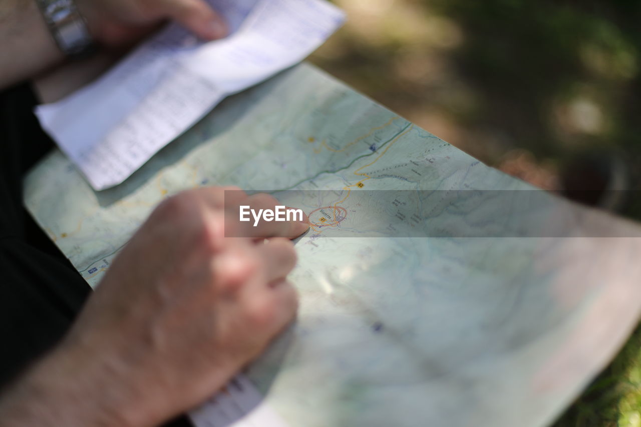 Midsection of man holding paper and maps