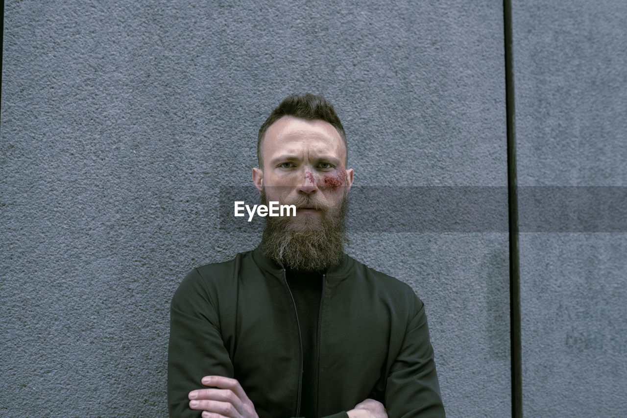 Hipster man with beard and cinema makeup posing on the street and looking at camera