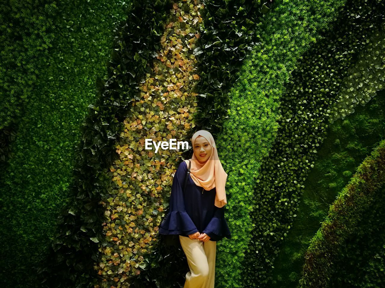 Portrait of woman in hijab standing by plants at park