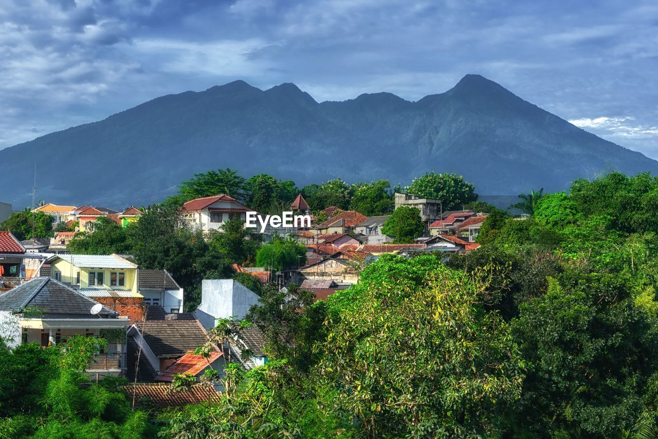 Houses and trees against mountains