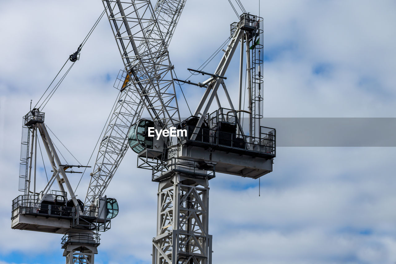 LOW ANGLE VIEW OF CRANES AT CONSTRUCTION SITE AGAINST SKY