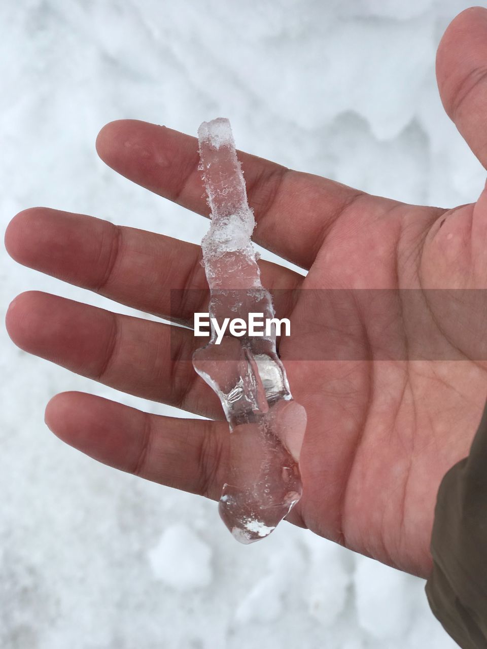 Cropped hand holding ice during winter