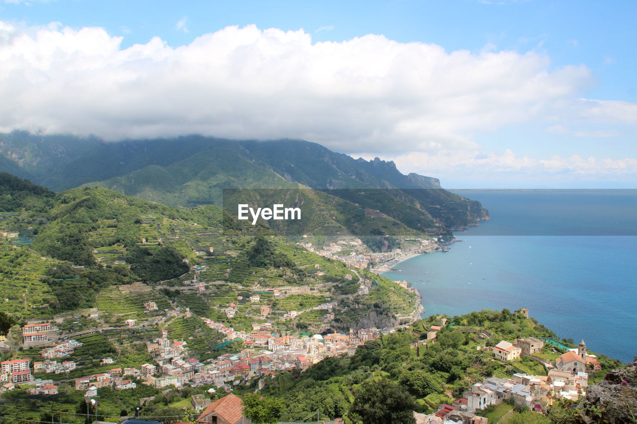 Scenic view of sea by townscape against sky