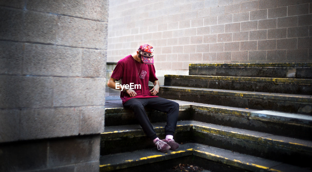 FULL LENGTH OF MAN SITTING ON STAIRCASE