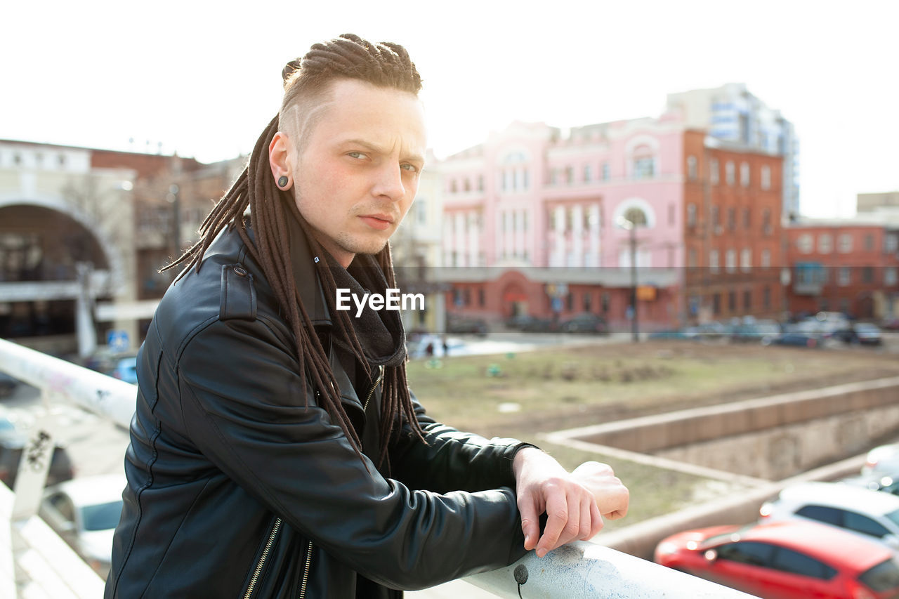 Portrait of serious hipster standing at terrace in city