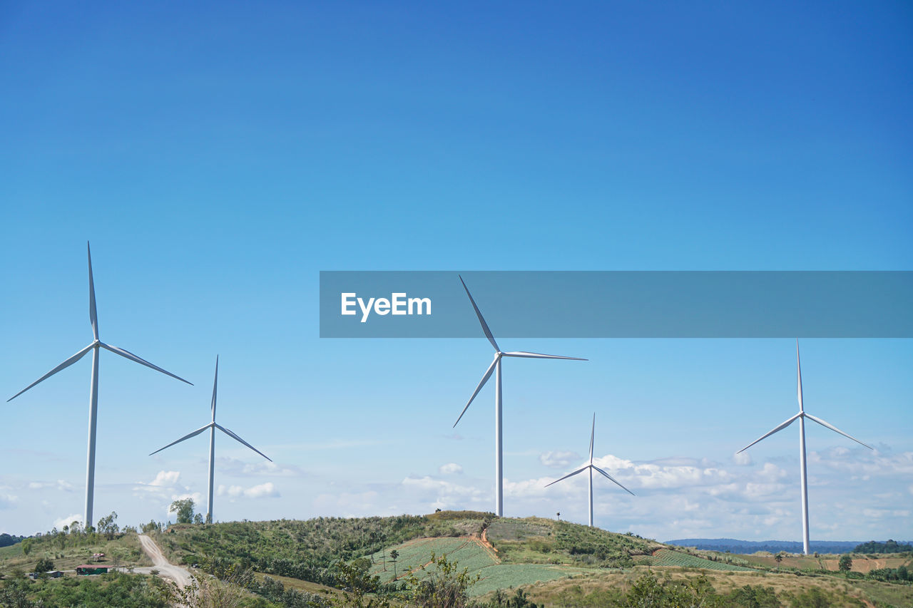 WINDMILLS ON FIELD AGAINST CLEAR SKY