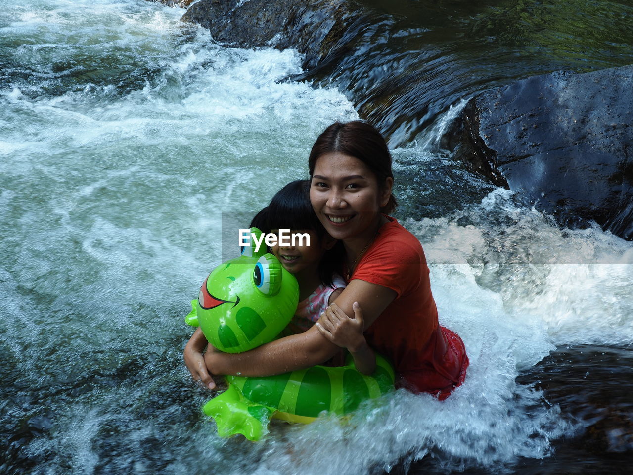 Portrait of happy mother with daughter in river