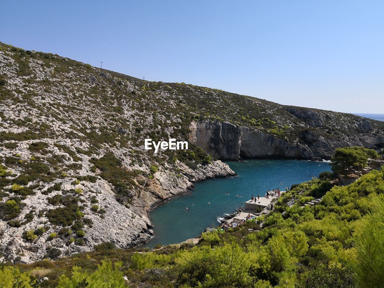 Scenic view of sea and mountains against clear blue sky