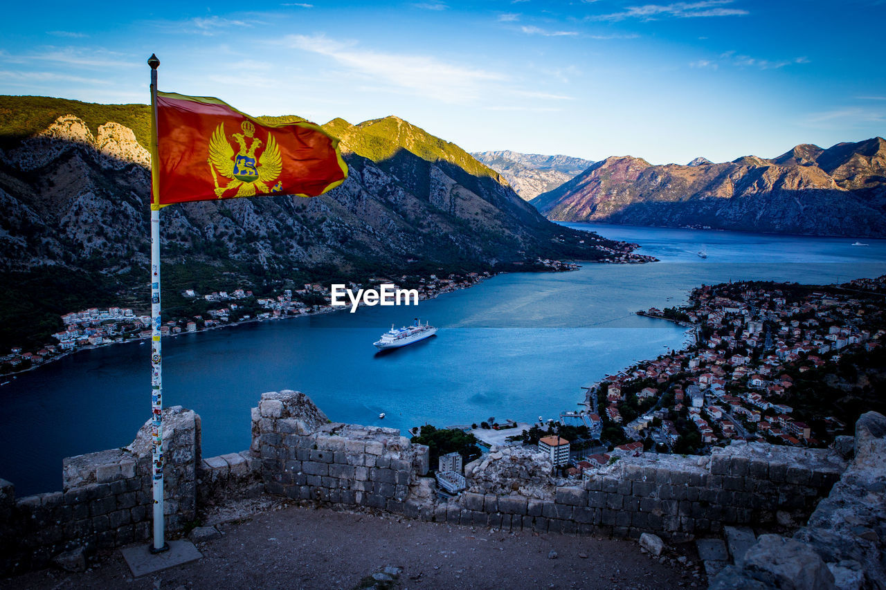 Montenegrin flag waving against river and mountains
