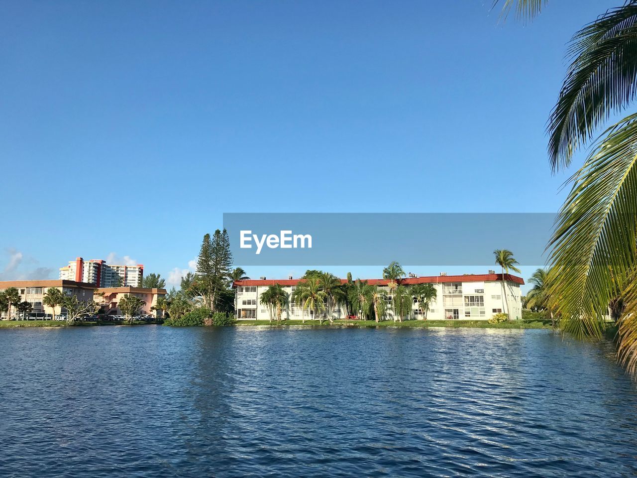 Buildings by lake against blue sky