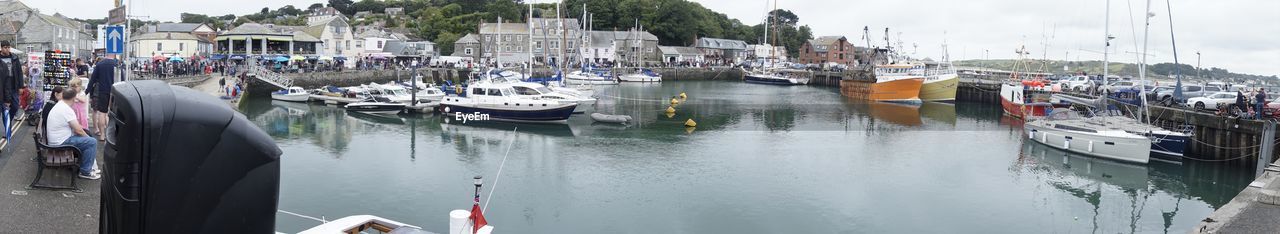 BOATS MOORED IN HARBOR AGAINST SKY