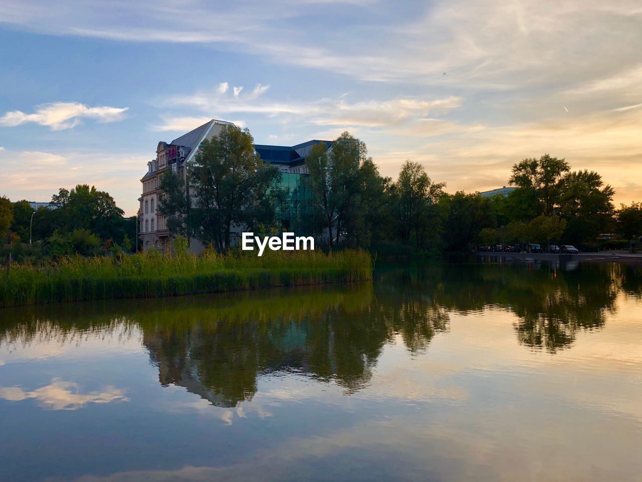 REFLECTION OF BUILDING ON LAKE AGAINST SKY