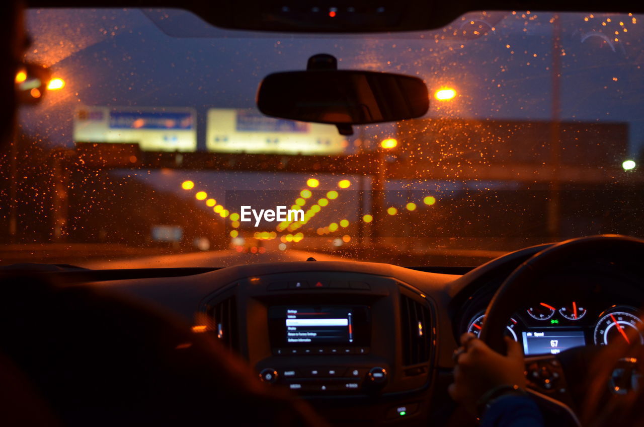 Cropped image of person driving car at night