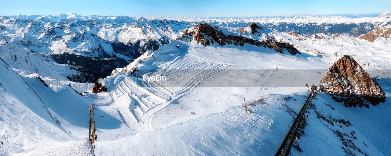 Wide angle large area panorama of rocky austria alps in sunny winter with skiing tracks