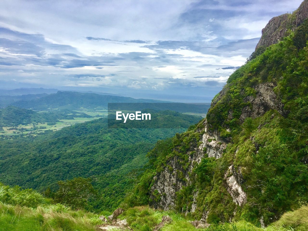 Green mountains against cloudy sky