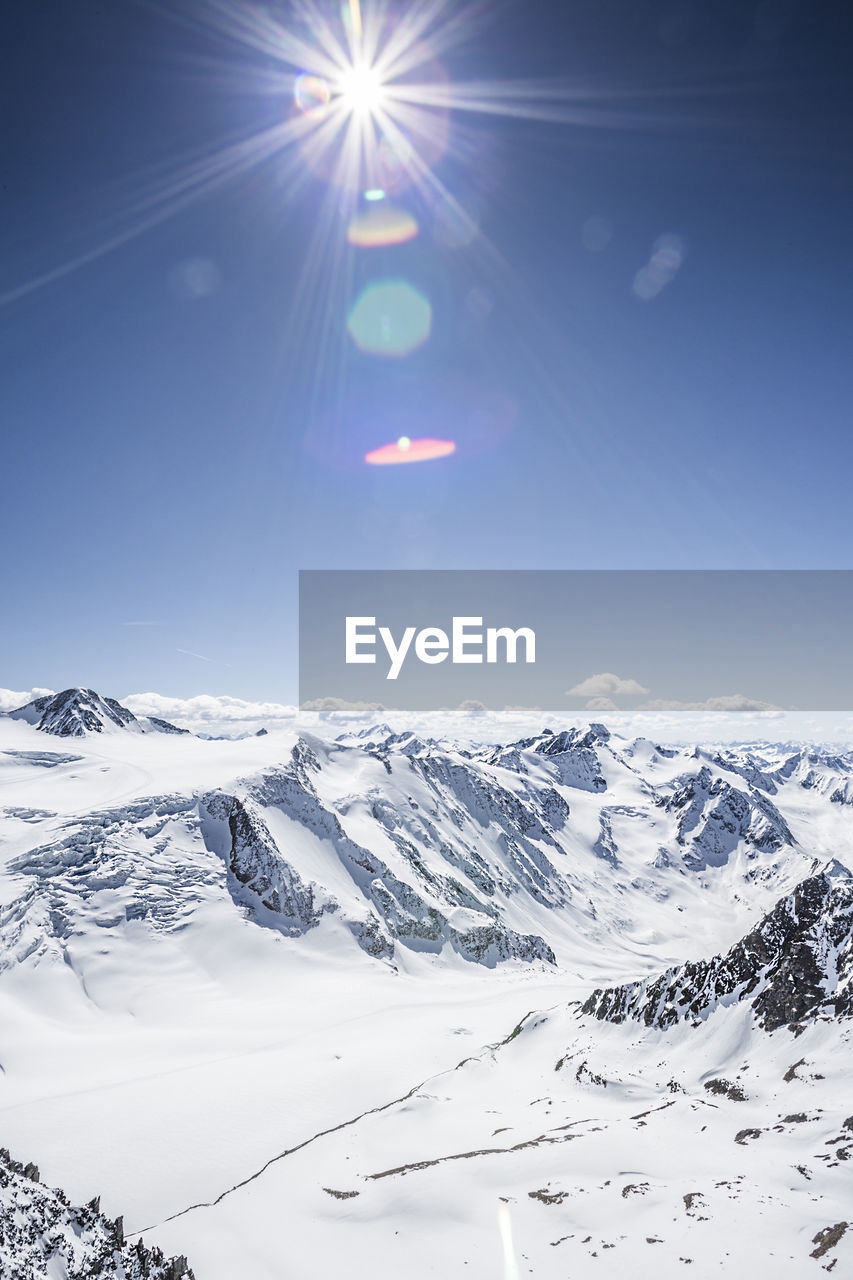 Scenic view of snowcapped mountains against blue sky