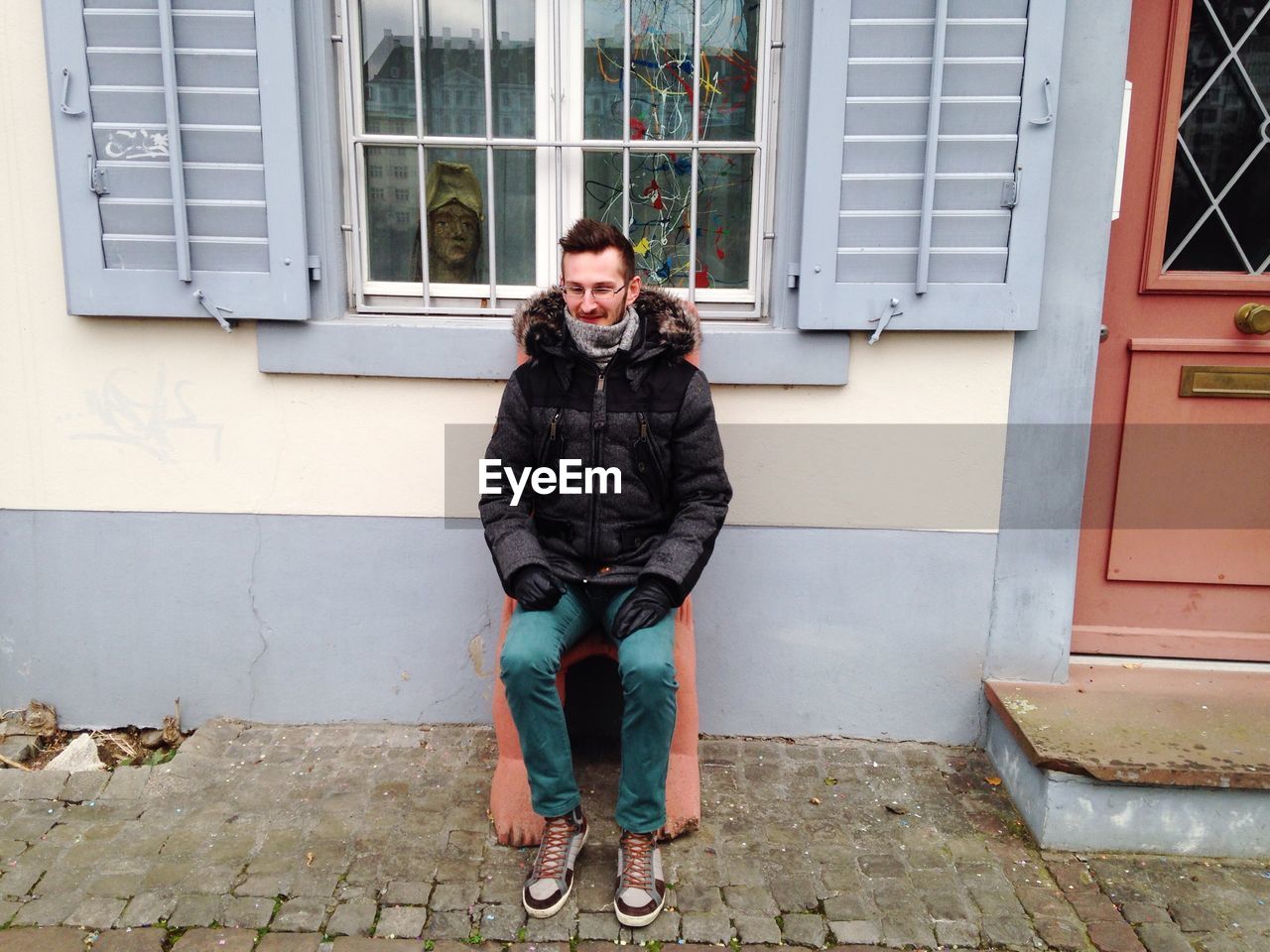 Smiling man sitting on chair outside house