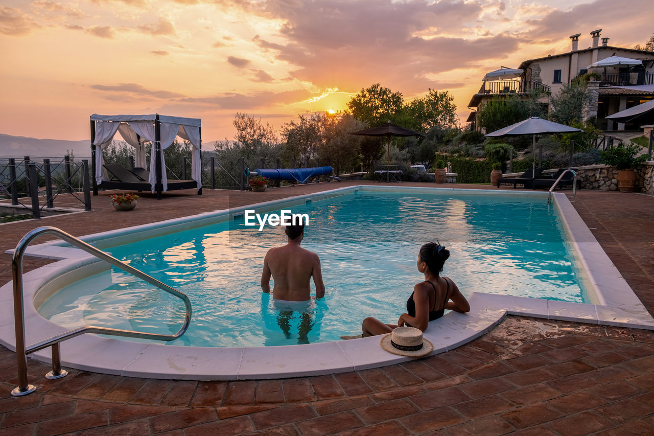 Rear view of couple in swimming pool against sky