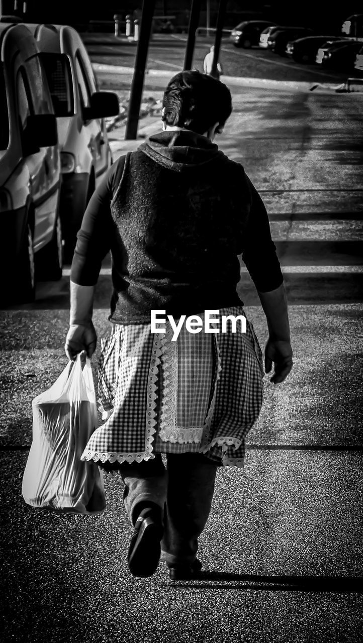 Rear view of woman walking on road